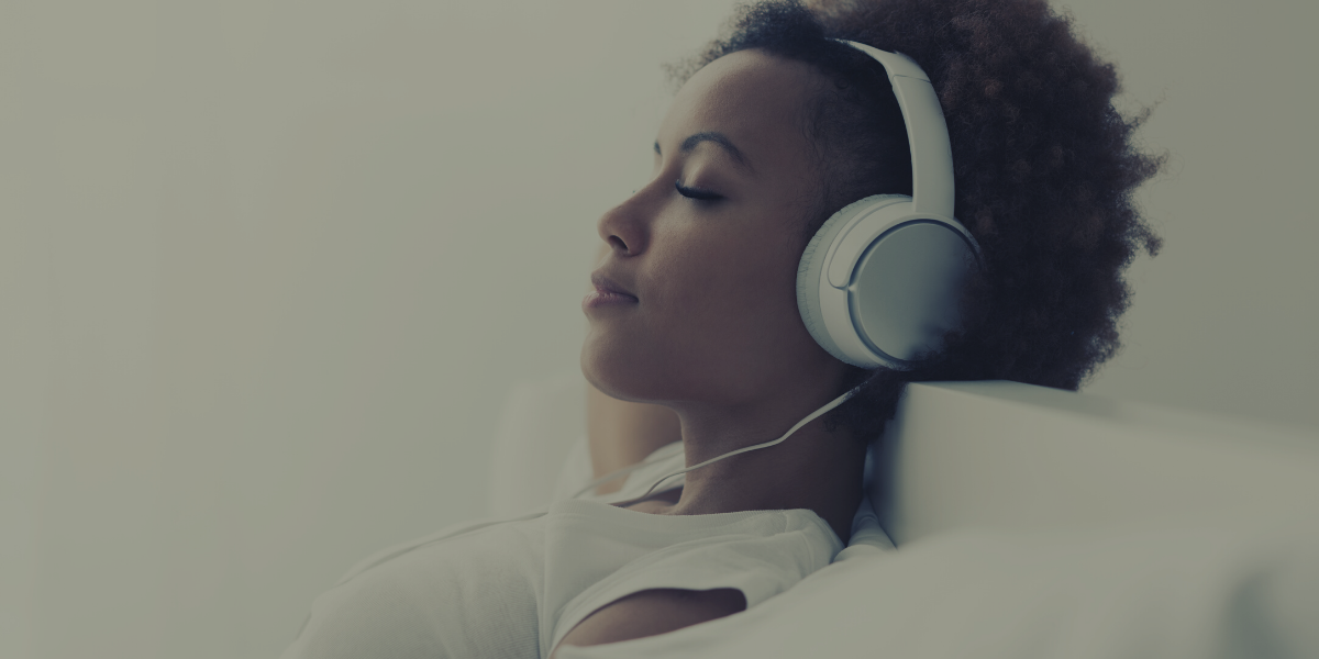 Eine Frau hört und entspannt zu Musik auf den Kopfhörern.