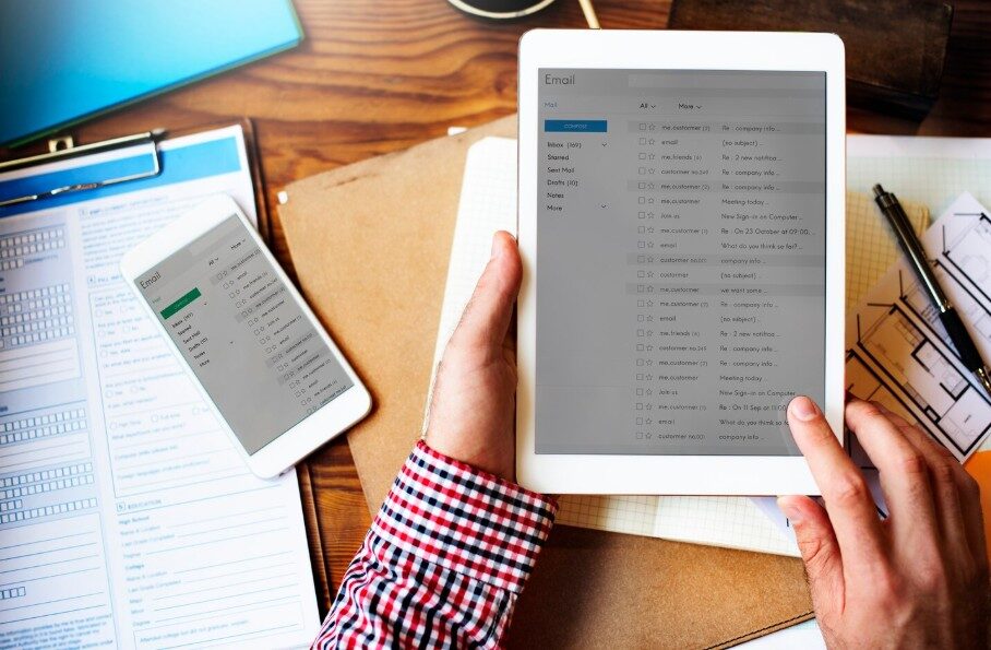 Produktionsleiter hält Tablet mit E Mail Posteingang über Formularen und Notizunterlagen für die Tagesdisposition