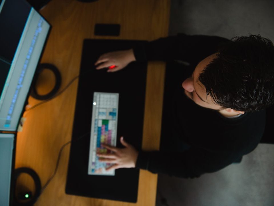 Editor arbeitet konzentriert an zwei Monitoren am Schnittplatz in der Postproduktion.